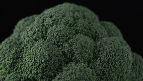 Raw broccoli head rotating over black background. Fresh broccoli cabbage rotating.