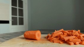 Close-up lifestyle video of cutting carrot with a chefs knife on a wooden board at home kitchen