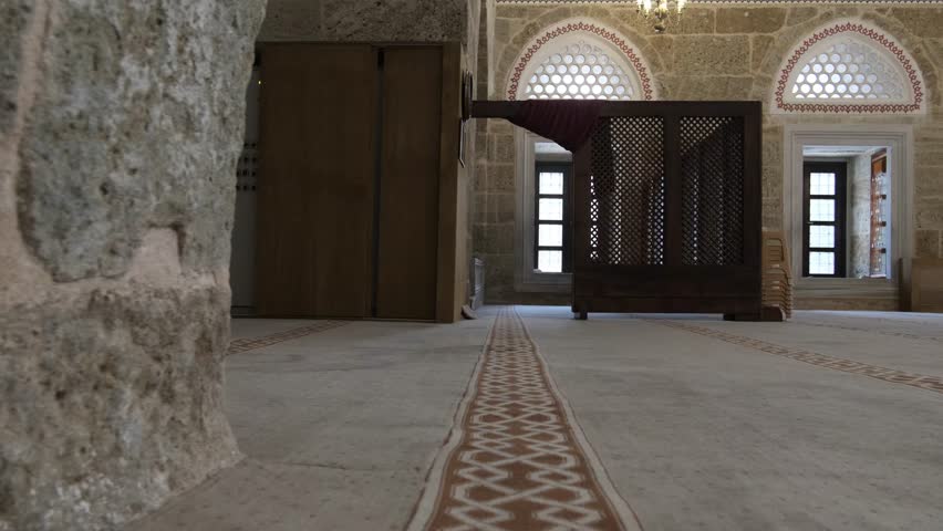 Old man in a hat visiting the interior of the historical mosque, muslim man visiting the ottoman mosque made of stone