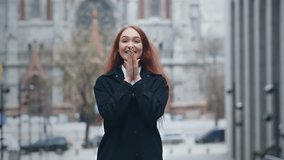 Excited red-haired girl standing on the street. Beautiful woman in coat expressing happiness