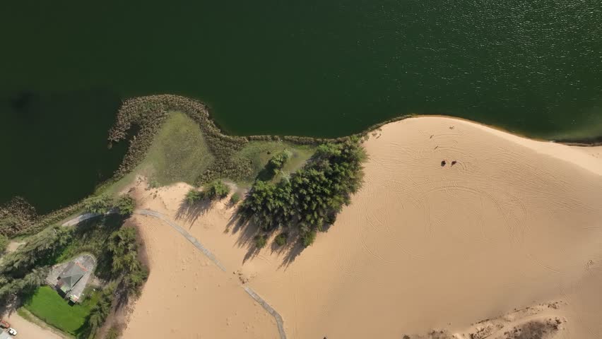 Get a unique perspective on the serene landscape of white sand dunes and lake with this stunning aerial footage