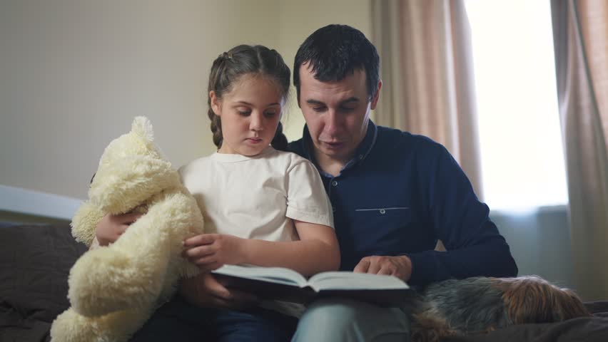 dad reading book to daughter in bedroom. happy family kid dream concept. father parent reads a book at night to his daughter child. dad and daughter care and guardianship lifestyle Royalty-Free Stock Footage #1102796583