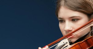 Panoramic camera movements reveal details of a classical musician, stringed instrument, hands with red-painted nails. Young woman playing violin with bow, blonde and fuchsia hair, nose piercing, shoul