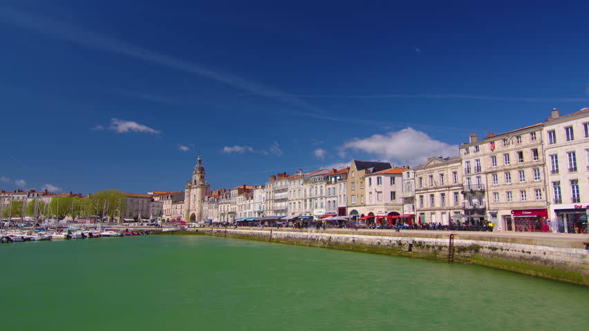 Time Lapse of the harbor in La Rochelle France. The famous French city on the ocean. Sunny summer day, clouds are moving in the background. Crowds of tourists walk the streets