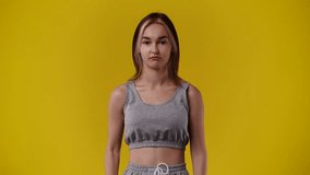 4k video of one girl who crosses her arms and responds negatively to something over yellow background.