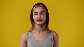 4k slow motion video of one girl showing thumbs up and smiling over yellow background.
