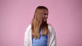 4k video of one girl with negative facial expression over pink background.