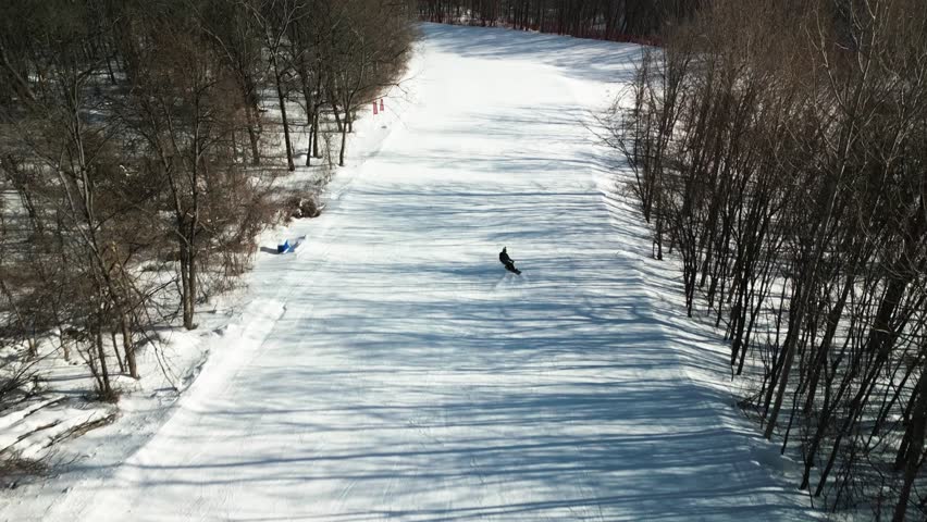 Aerial gootage of a young snowboarder doing downhill ride at yabuli resort 