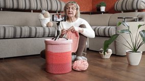 A woman blogger records a video about knitting with a smartphone on a tripod, in her room. Blog, lessons and hobby concepts