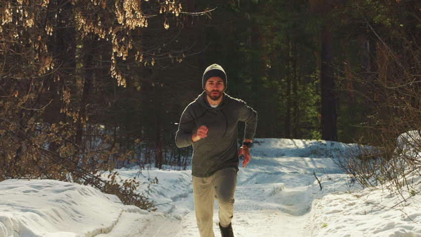 Man runs through the winter forest, the concept of sports and a healthy lifestyle. Royalty-Free Stock Footage #1102805177