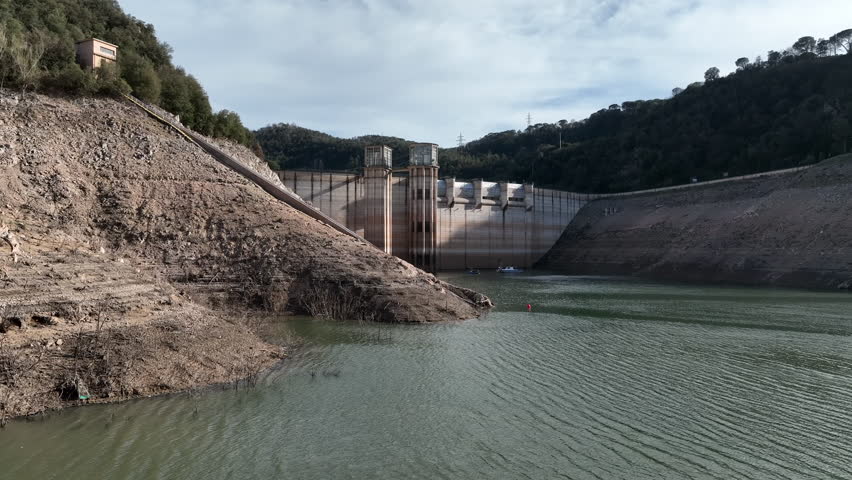 Extreme low water levels at dam reservoir during drought season, aerial view
