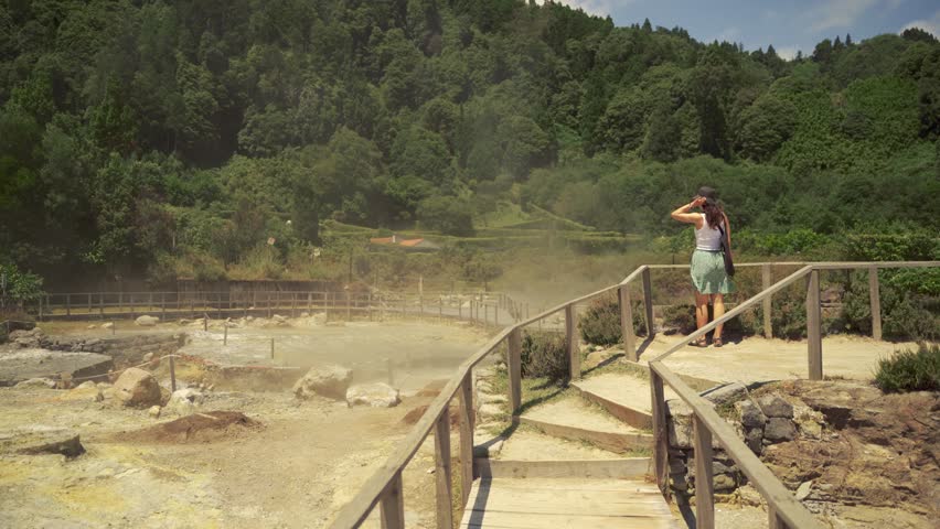 A woman is observing the nature park and volcanic activity from the wooden paths of Geysir Park.