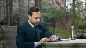 Businessman signing some urgent papers in a park near office building during lunch break - Powered by Shutterstock - Get 15% off with code: PIKWIZARD15