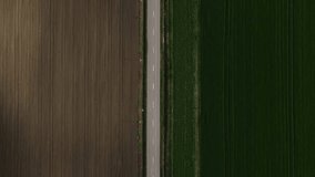 One blue car traveling alone on countryside road top down view follow vehicle aerial footage.