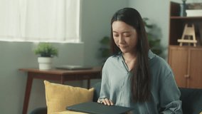 Happy attractive young Asian woman using laptop video conference call with friends or family. Beautiful female smile looking at notebook computer screen talking sit on couch in cozy living room