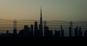 Dubai business center with Burj Khalifa among many glass skyscrapers at dusk, video from the moving car window