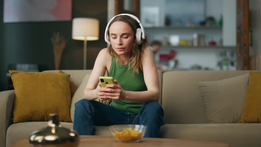 Relaxed girl listening headphones music at sofa interior. Positive lady moving in song beat holding smartphone. Headset carefree woman enjoying weekend in modern house. Female hipster dancing head Royalty-Free Stock Footage #1102818259