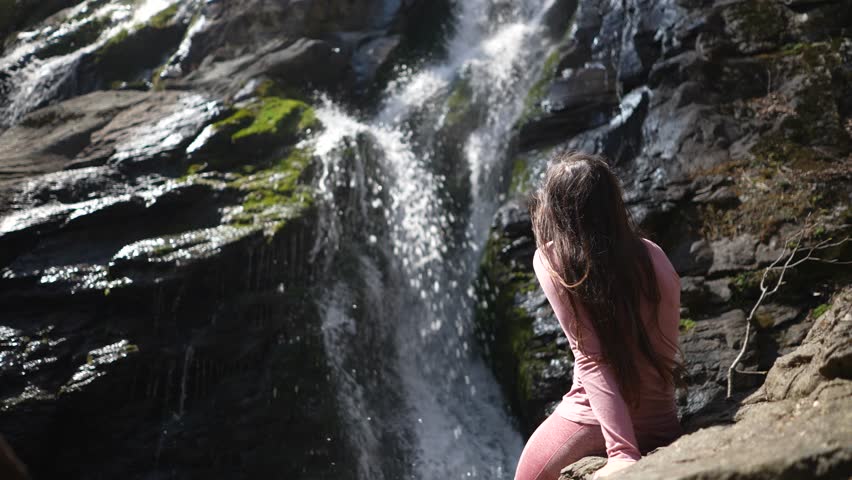 Pretty young woman happy and smiling pointing to beautiful waterfall in Shenandoah National Park in Blue Ridge mountains, Virginia, VA.