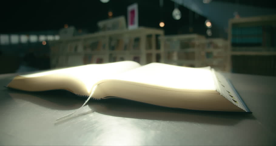 Glowing pages of an open book close-up. Reading knowledge concept. Cinematic light at university library. Royalty-Free Stock Footage #1102819347