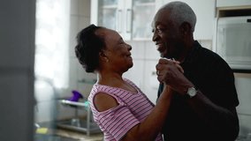 A happy African American senior mature couple dancing together in kitchen. A vibrant black husband and wife holding hands - Powered by Shutterstock - Get 15% off with code: PIKWIZARD15