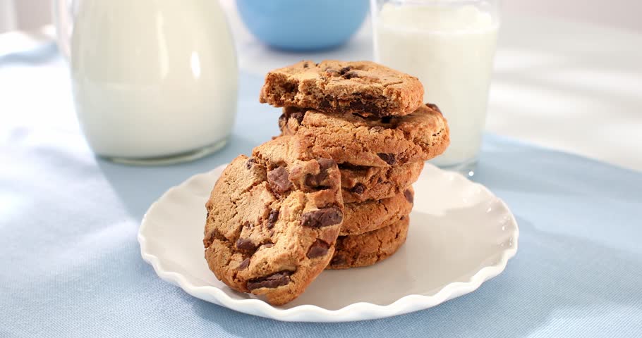 cookies with milk on a blue background. american chocolate chip cookie closeup. pastries on the table. sweets on a plate on a sunny day