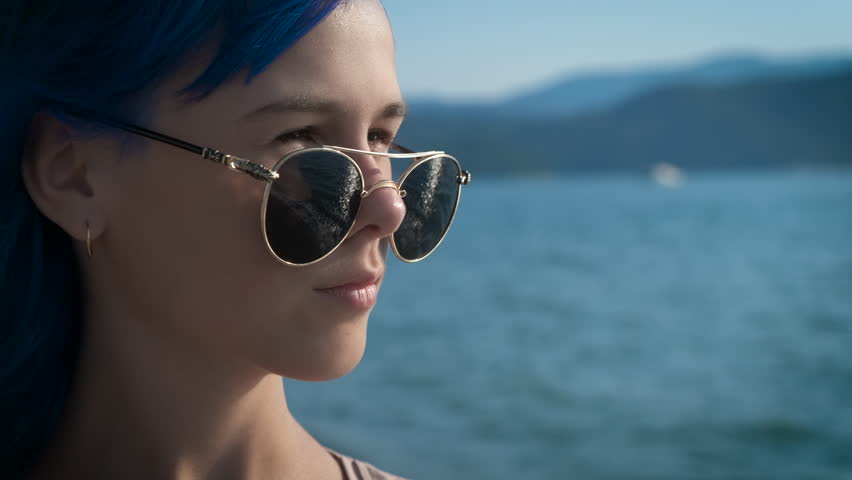 A cute girl takes off her sunglasses and looks at the camera.