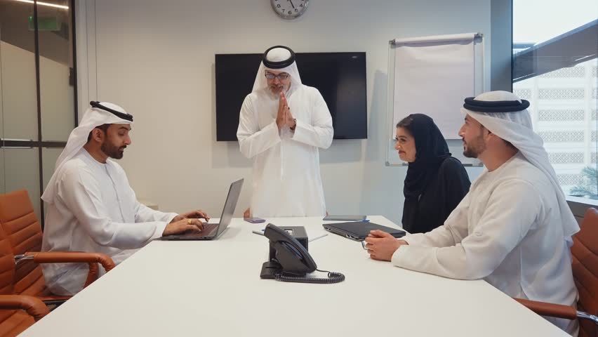 Business team at work in a office in Dubai. Locals from united arab emirates working on a new project wearing the formal traditional white outfit	 | Shutterstock HD Video #1102828335