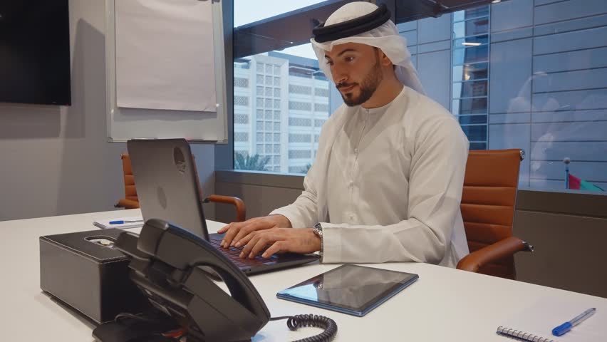 Business team at work in a office in Dubai. Locals from united arab emirates working on a new project wearing the formal traditional white outfit	 Royalty-Free Stock Footage #1102828391