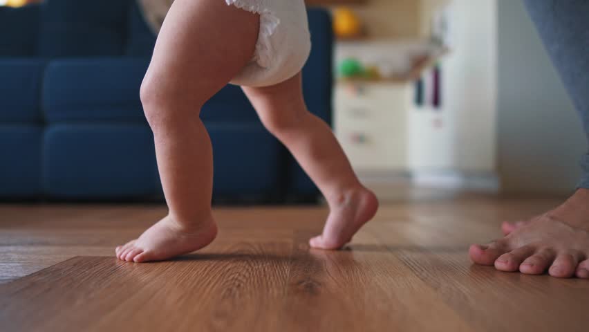 baby takes first steps. happy family first steps kid dream concept. father teaches baby to take first steps close-up. newborn baby boy learning to lifestyle step foot. father teaching daughter