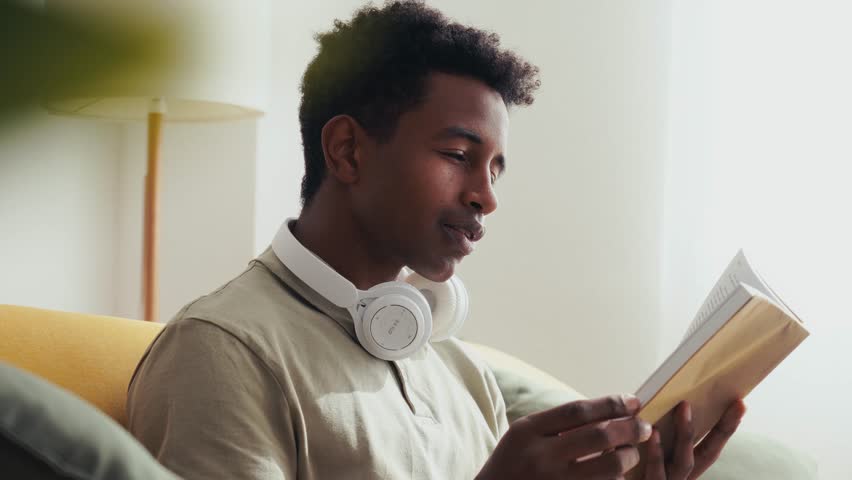 African American man reading book in living room