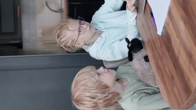 Online school class, siblings pupils boy and girl learning together remotely online at home, looking to laptop, speaking with teacher or tutor using internet, vertical video