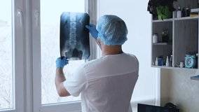Doctor in the office with an x-ray of a man's back. The doctor analyzes the x-ray of the spine. Diagnosis and therapy of osteochondrosis. The surgeon diagnoses the spine. Spinal injury on ultrasound - Powered by Shutterstock - Get 15% off with code: PIKWIZARD15