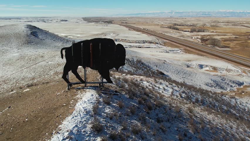 Wyoming - circa 2023 - excellent aerial footage circling towards an enormous sign in the shape of a buffalo on a wintry mountaintop in wyoming.