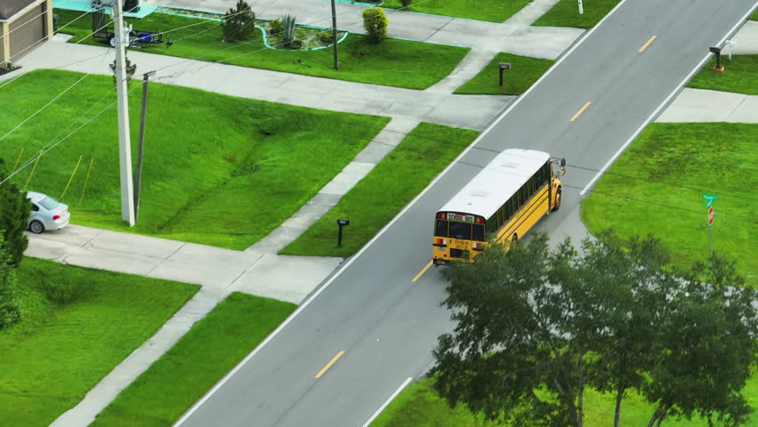 Top view of classical american yellow school bus driving on rural town street for picking up kids for their lessongs in early morning. Public transport in the USA