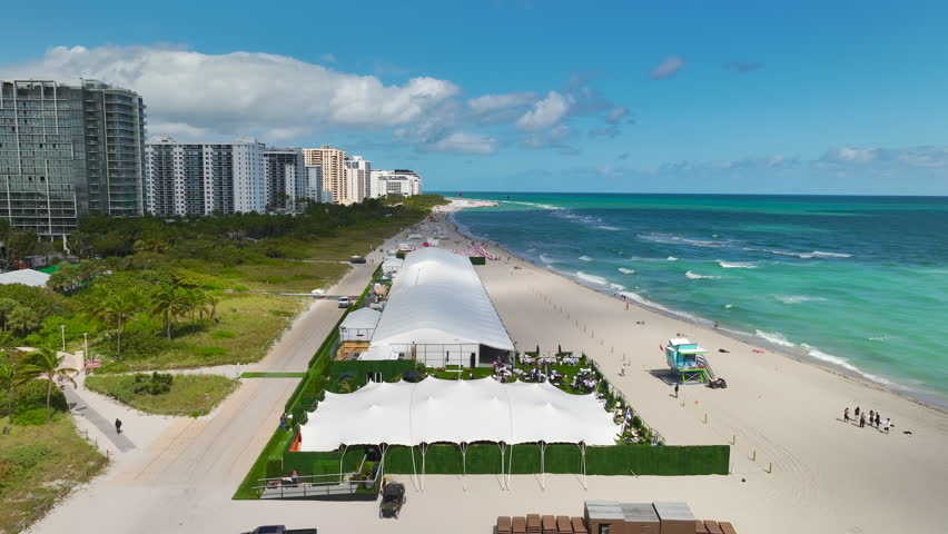 Aerial view of South Beach sandy surface with tourists relaxing on hot Florida sun. Miami Beach city with high luxury hotels and condos. Tourism infrastructure in southern USA