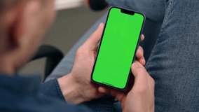 Man Uses Phone With Green Screen Mock Up Display Sitting At Workplace In Office. Smartphone With Green Screen Close Up