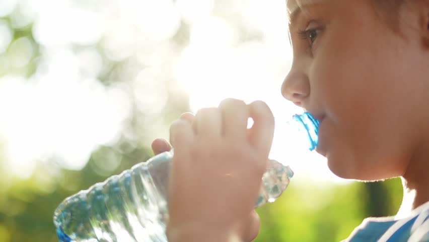 child drinking water from plastic bottle. water shortage problem on earth concept. water shortage problem lifestyle on earth concept. kid drinks water in nature from a bottle glare of the sun summer Royalty-Free Stock Footage #1102846837