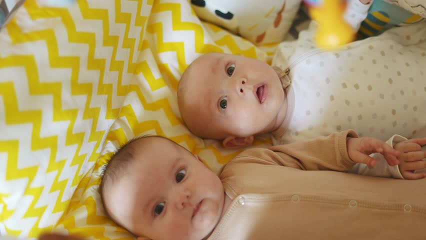 two twins lie in bed. happy family fun kid dream concept. cute twins lie in bed in the bedroom in the evening smile look at the toy newborn boy and girl brother and sister Royalty-Free Stock Footage #1102846871