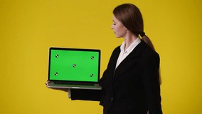 4k video of one girl using chroma key laptop and showing thumbs down over yellow background.