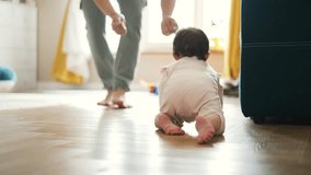 Happy and curious child explores his house by crawling on parquet floor.Father cheers his child up by clapping his hands.Baby crawls across floor towards his parent.Baby learn to move on floor at home - Powered by Shutterstock - Get 15% off with code: PIKWIZARD15