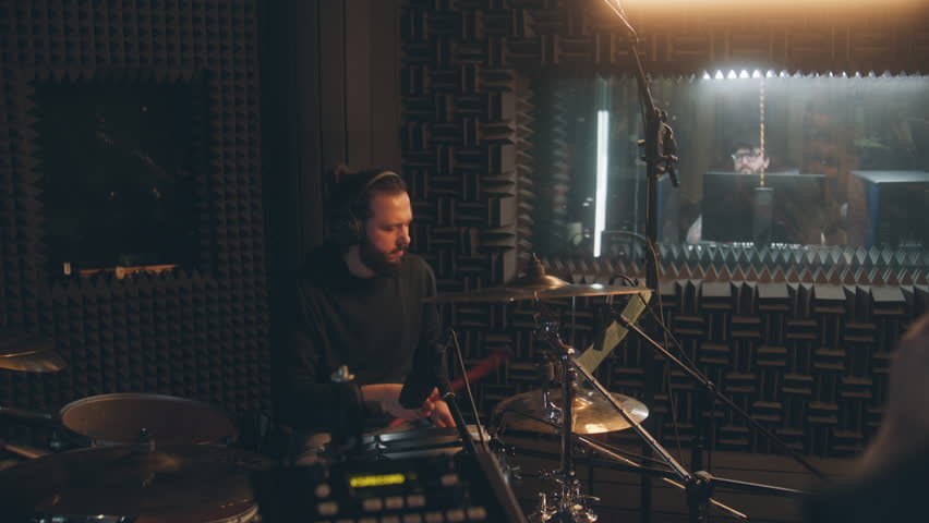 Musical band records song for album in sound recording studio. Male drummer in headphones plays a drum kit. Audio engineer on background. Work in the music recording room. Music production concept. Royalty-Free Stock Footage #1102856865