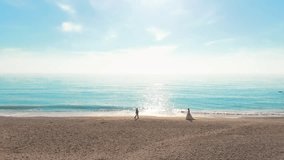 Bride and groom meet each other along the sand of the shore against the backdrop of sea waves and the sun,backlit.Drone video of two people in love on the background of nature.people in love walk  - Powered by Shutterstock - Get 15% off with code: PIKWIZARD15