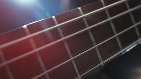 Bass Strings Hit with Finger Vibrate in Macro and Slow Motion. Camera Moves along the Guitar's Neck, with a Concert of Multicolored Lights in the Background. - Powered by Shutterstock - Get 15% off with code: PIKWIZARD15