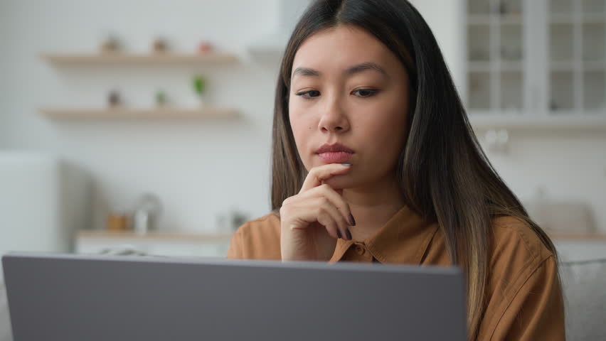 Smart pensive Asian chinese woman 30s businesswoman work from home kitchen thoughtful writer think business plan contemplate search media online on laptop doubtful korean girl thinking idea decision Royalty-Free Stock Footage #1102862061