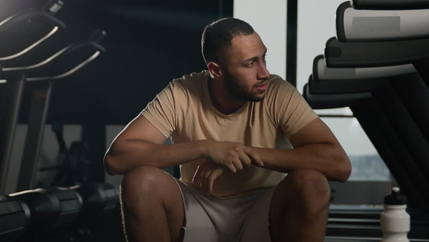 Tired african american athlete sportsman take break at sport gym exhausted sweaty runner hard breathing rest after cardio exercise running workout weary latino man guy sit on fitness treadmill relax Royalty-Free Stock Footage #1102862063