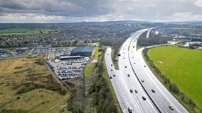 Aerial drone cinematic video footage of the M1 Motorway near the city of Wakefield, West Yorkshire, UK. Showing the busy motorway full of traffic and commercial buildings.
