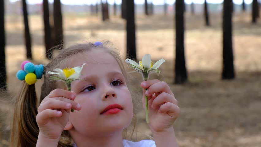 Cute girl  investigate details of nature, focused on flowers . Summer time outdoor kids activity and learning concept. 