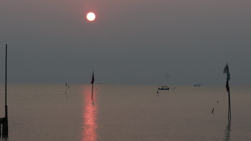 blur nature video Of the sun that is setting back on the horizon in the sea, there is a beautiful colorful sky of nature, there are medium-large fishing boats out to fish during the day.