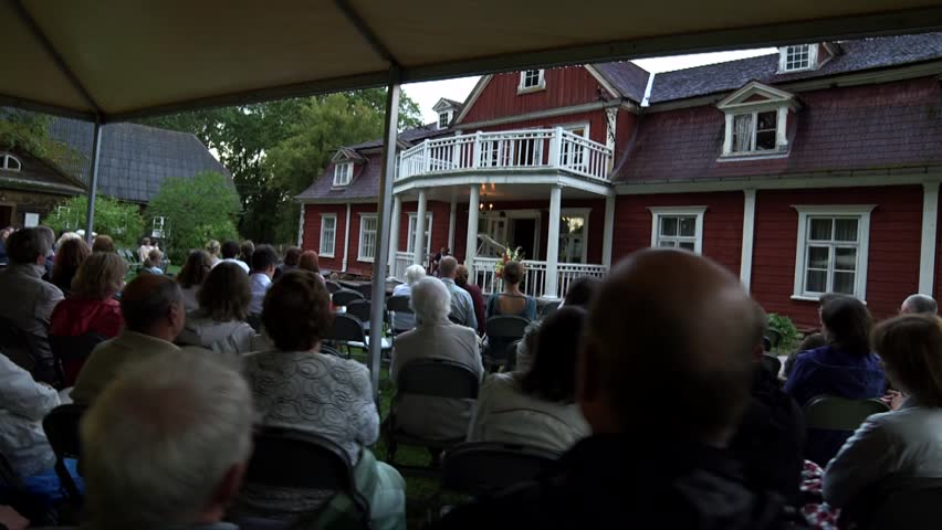 steadicam shot of a concert on the terrace of the manor with many spectators, camera from behind over heads