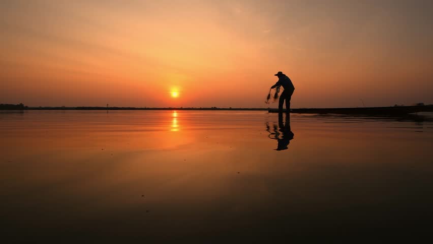 Silhouette fisherman throwing net casting fish in early morning with wooden boat fisherman life style.